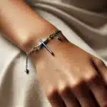 DALL·E 2024-11-25 20.25.21 – A close-up of a bracelet worn on a person’s wrist, featuring a horizontal cross with a delicate silver chain. There are two small dangling letters ‘J’